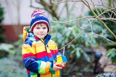 Küçük çocuk çocuk kuş evi kış aylarında beslenme için ağaç üzerinde asılı
