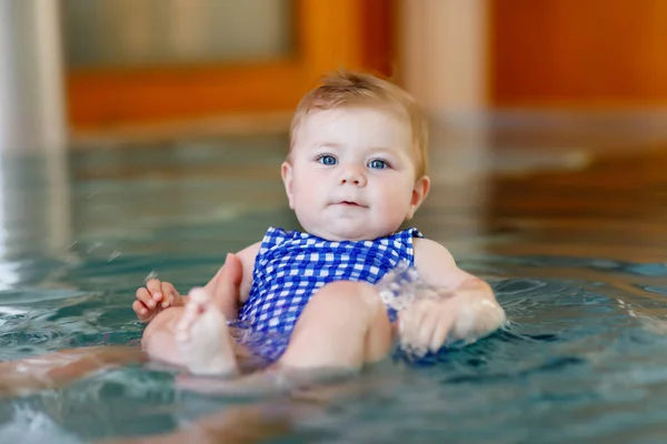 Lindo bebé pequeño aprendiendo a nadar en una piscina cubierta — Foto de Stock