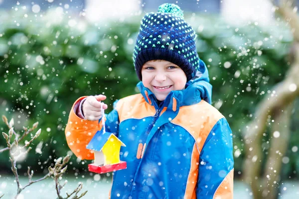 Niño colgando casa de pájaros en el árbol para alimentarse en invierno — Foto de Stock