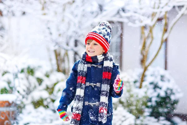 Rolig liten pojke i färgglada kläder spelar utomhus under stark snöfall — Stockfoto