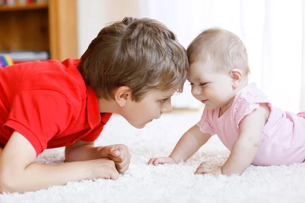 Happy little kid boy with newborn baby girl, cute sister. Siblings. Brother and baby playing together — Stock Photo, Image