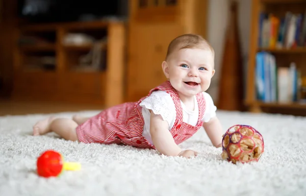 Niedliches Baby, das mit buntem Rasselspielzeug spielt. Kleines Mädchen blickt in die Kamera und krabbelt — Stockfoto