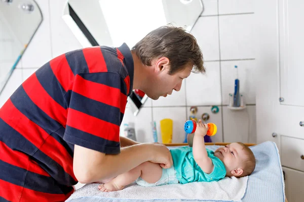 Loving father changing diaper of his newborn baby daughter. — Stock Photo, Image