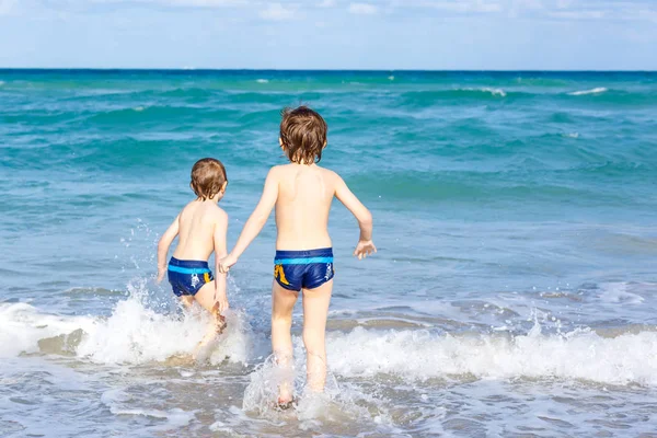 Due ragazzini che corrono sulla spiaggia dell'oceano in Florida — Foto Stock