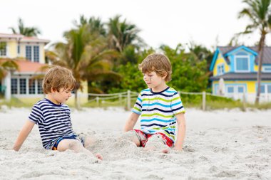 İki küçük çocuk tropik sahilde eğleniyor.