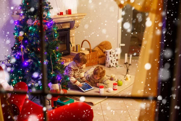 Duas crianças sentadas em uma lareira em casa no Natal — Fotografia de Stock