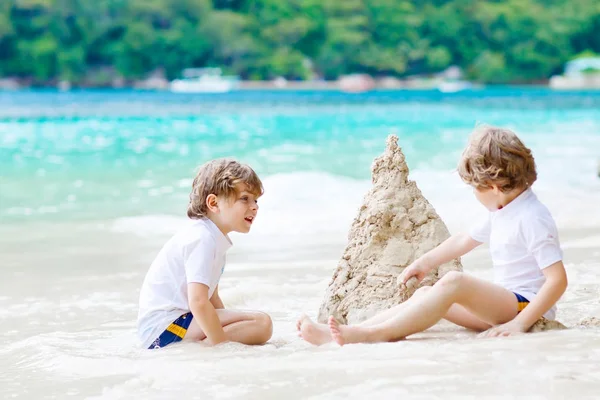 Двоє хлопчиків будують піщаний замок на тропічному пляжі — стокове фото
