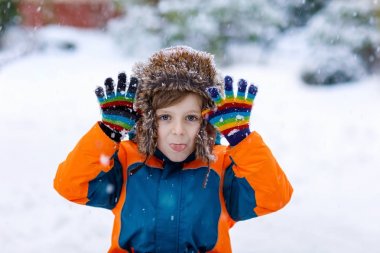 Mutlu çocuk kışın karla eğleniyor.
