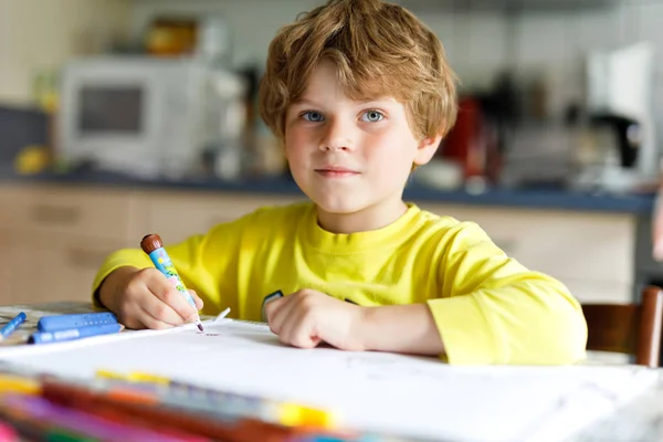 Niño cansado en casa haciendo deberes escribiendo cartas con bolígrafos coloridos —  Fotos de Stock