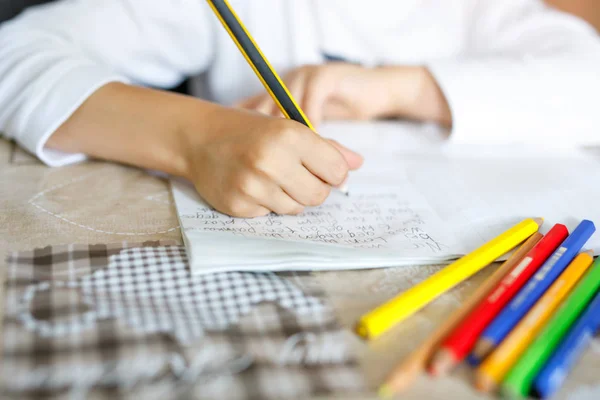 Kind, das Hausaufgaben macht und einen Essay schreibt. Grund- oder Grundschulklasse. Nahaufnahme von Händen und Buntstiften — Stockfoto