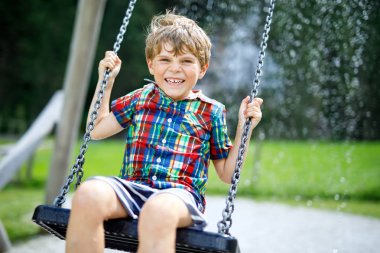 Açık sahada yağmur sırasında eğlenmek zinciri salıncak ile komik çocuk çocuk