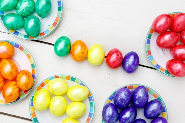 Påskägg på trä bakgrund. Färgglada ägg i olika färger - röd, gul, orange, lila och grön. — Stockfoto