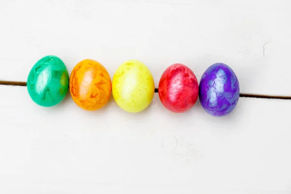 Påskägg på trä bakgrund. Färgglada ägg i olika färger - röd, gul, orange, lila och grön. — Stockfoto