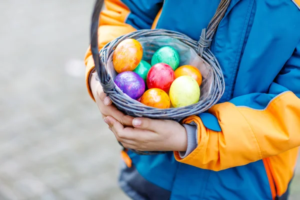 Primer plano de las manos de un niño pequeño con coloridos huevos de Pascua en la cesta —  Fotos de Stock