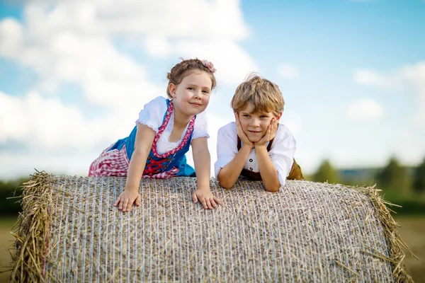 Two kids, boy and girl in traditional Bavarian costumes in wheat field — Stock Photo, Image