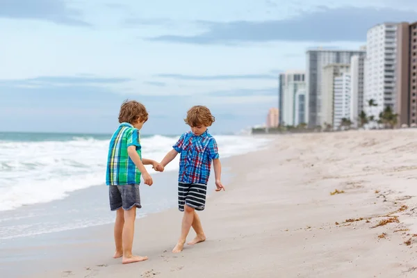 Due ragazzini che corrono sulla spiaggia dell'oceano — Foto Stock