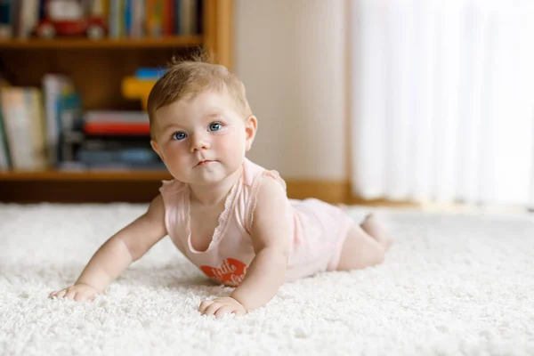 Pequeña niña divertida levantando cuerpo y aprendiendo a gatear. —  Fotos de Stock