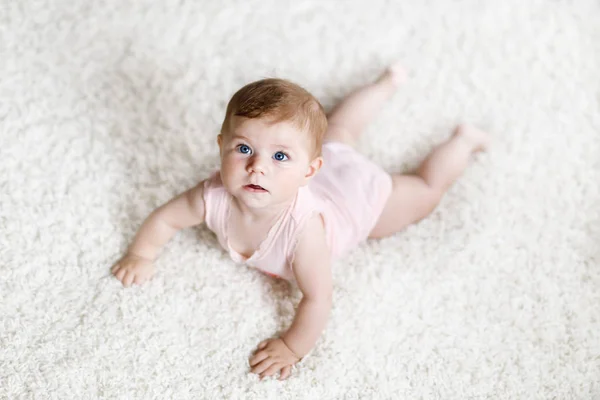 Little funny baby girl lifting body and learning to crawl. — Stock Photo, Image