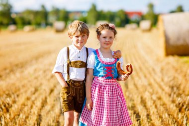 Two kids, boy and girl in traditional Bavarian costumes in wheat field clipart