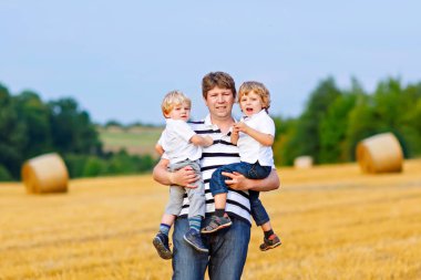 Babam yazın buğday tarlasında iki çocuğu kollarıyla tutuyor.