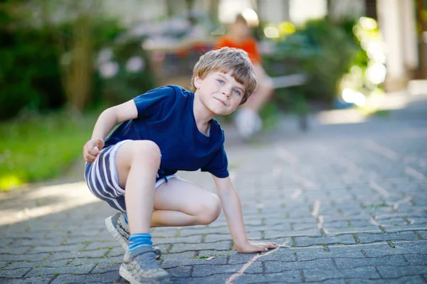 Liten blond funny kid pojke spela hoppa hage på lekplats utomhus — Stockfoto