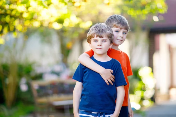 Two little active school kids boys, twins and siblings hugging on summer day — Stock Photo, Image