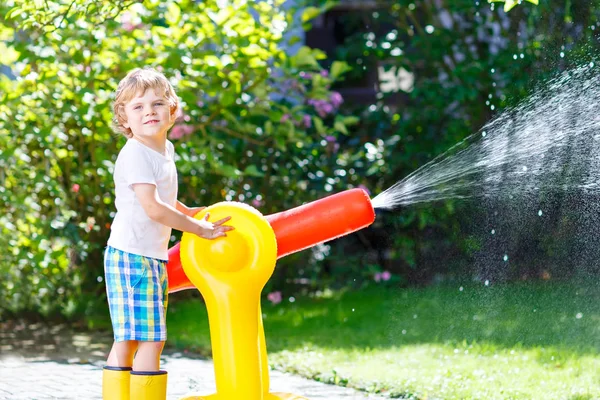Niño jugando con un aspersor de agua de manguera de jardín — Foto de Stock