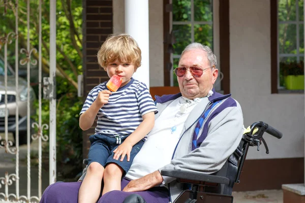 Kid boy and grandfather on wheelchair eating ice cream — Stock Photo, Image