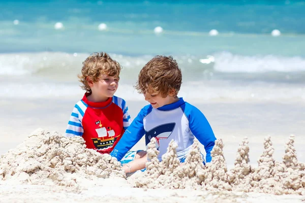 Kum kale sızarım tropikal plaj üzerinde iki çocuk çocuklar — Stok fotoğraf