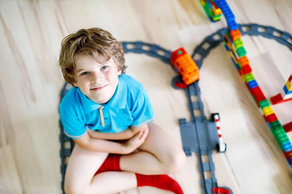 Lille blond kid dreng leger med farverige plast blokke og skabe togstation - Stock-foto