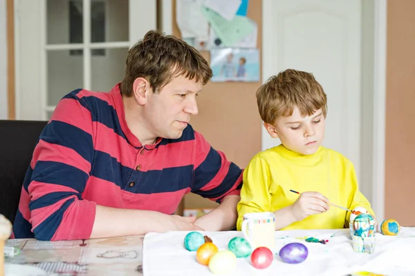 Little blond preschool kid boy and father coloring eggs for Easter holiday — Stock Photo, Image