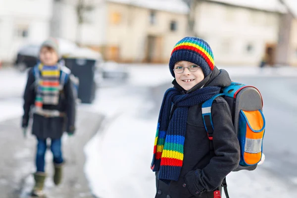 Два маленьких мальчика из начального класса идут в школу во время снегопада — стоковое фото