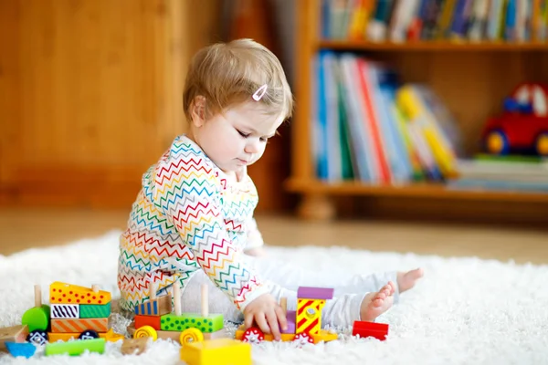 Schattig leuk mooie babymeisje spelen met houten onderwijsspeelgoed thuis of kwekerij. Peuter met kleurrijke trein — Stockfoto