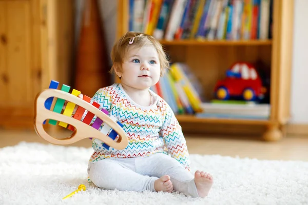 Adorable linda y hermosa niña jugando con juguetes educativos de música de madera en casa o en el vivero. Niño pequeño con xilofón colorido —  Fotos de Stock