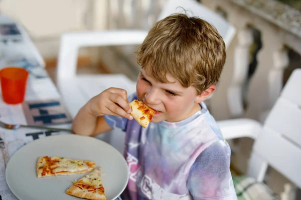 Lindo niño preescolar saludable come pizza fresca sentado en la terraza en verano, al aire libre —  Fotos de Stock