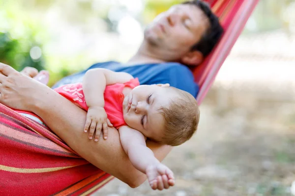 Bonito adorável bebê menina de 6 meses e seu pai dormindo em paz na rede no jardim ao ar livre — Fotografia de Stock