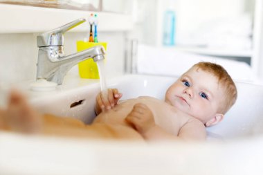 Alarak şirin bebek yıkama lavabo banyo ve musluk suyu yakala.
