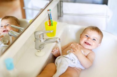 Alarak şirin bebek yıkama lavabo banyo ve musluk suyu yakala.