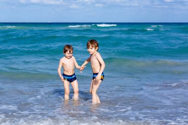 Okyanus plaj üzerinde çalışan iki çocuk çocuklar. Küçük çocuklar eğleniyor