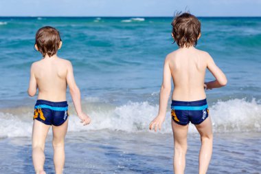 Okyanus plaj üzerinde çalışan iki çocuk çocuklar. Küçük çocuklar eğleniyor