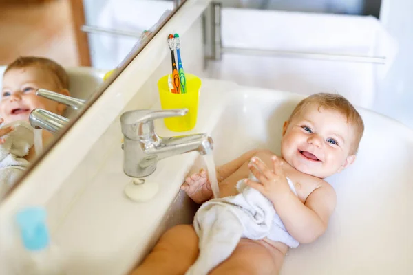 Schattige schattig baby nemen bad in wassen gootsteen en waterkraan pak. — Stockfoto