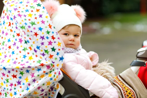 Schattig klein mooie babymeisje, zittend in de kinderwagen of wandelwagen op koude dag — Stockfoto