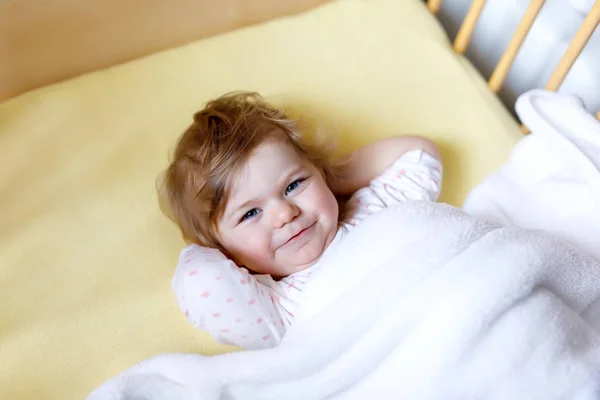Aranyos kis baba lány feküdt a kiságy, lefekvés előtt. Boldog nyugodt gyermek ágy. Megyek aludni. Békés, mosolygó gyermek — Stock Fotó