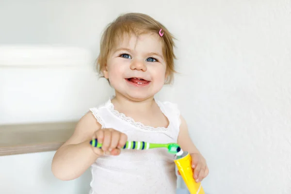 Malá holčička držící kartáček a čistící první zuby. Batole se učí čistit mléčné zuby. — Stock fotografie