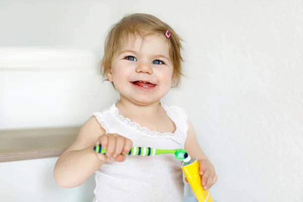 Menina bebê segurando escova de dentes e escovando os primeiros dentes. Criança aprendendo a limpar o dente de leite. — Fotografia de Stock