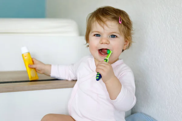 Little baby girl holding toothbrush and brushing first teeth. Toddler learning to clean milk tooth. — Stock Photo, Image