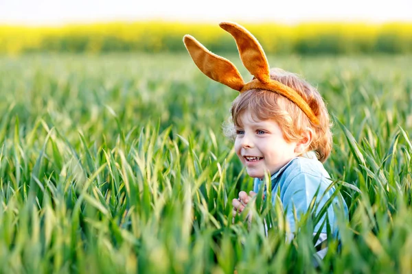 Menino pequeno se divertindo com a tradicional caça ao ovo de Páscoa — Fotografia de Stock