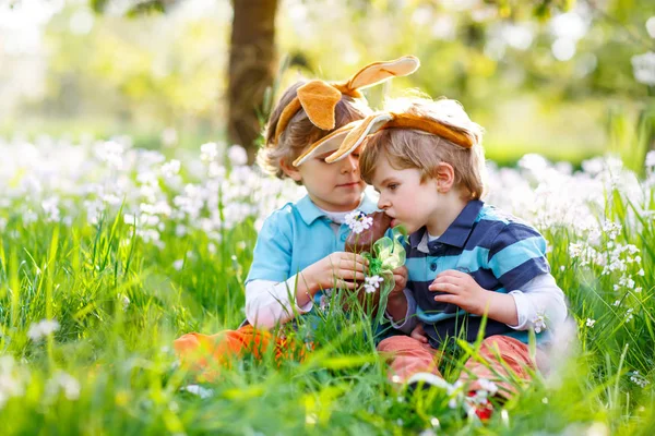 Dos amiguitos en orejas de conejo de Pascua comiendo chocolate —  Fotos de Stock