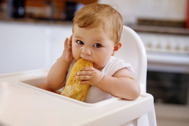 Küçük şirin bir kızın portresi yüksek sandalyede oturup beslenmeyi bekliyor.