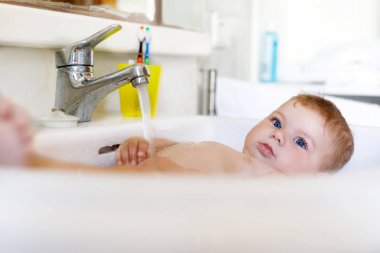 Alarak şirin bebek yıkama lavabo banyo ve musluk suyu yakala.